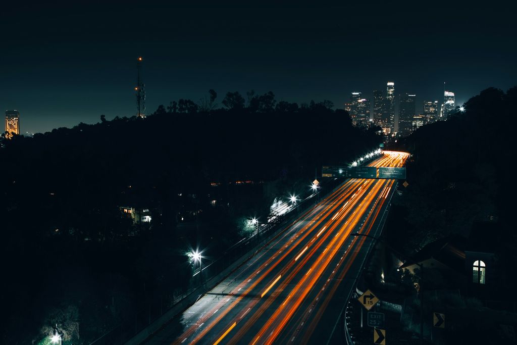 Interstate traffic streaming toward a city skyline after dark